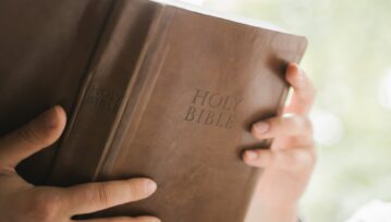 Person Holding Brown Holy Bible